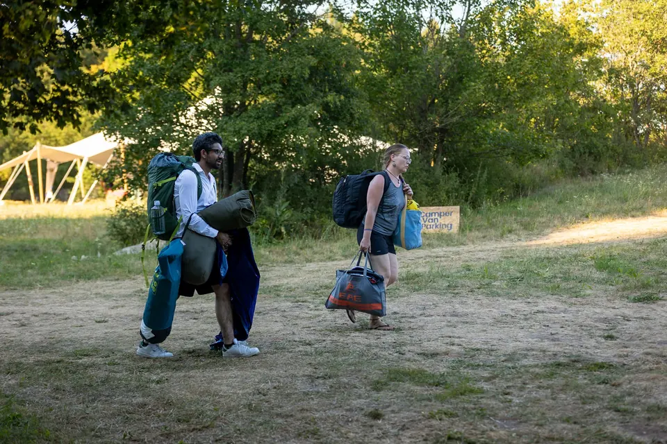 Festival-goers walking into camp with backpacks and sleeping mats